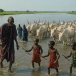 Dinka families crossing the Bahr el Ghazal River with cattle during a seasonal migration in South Sudan.